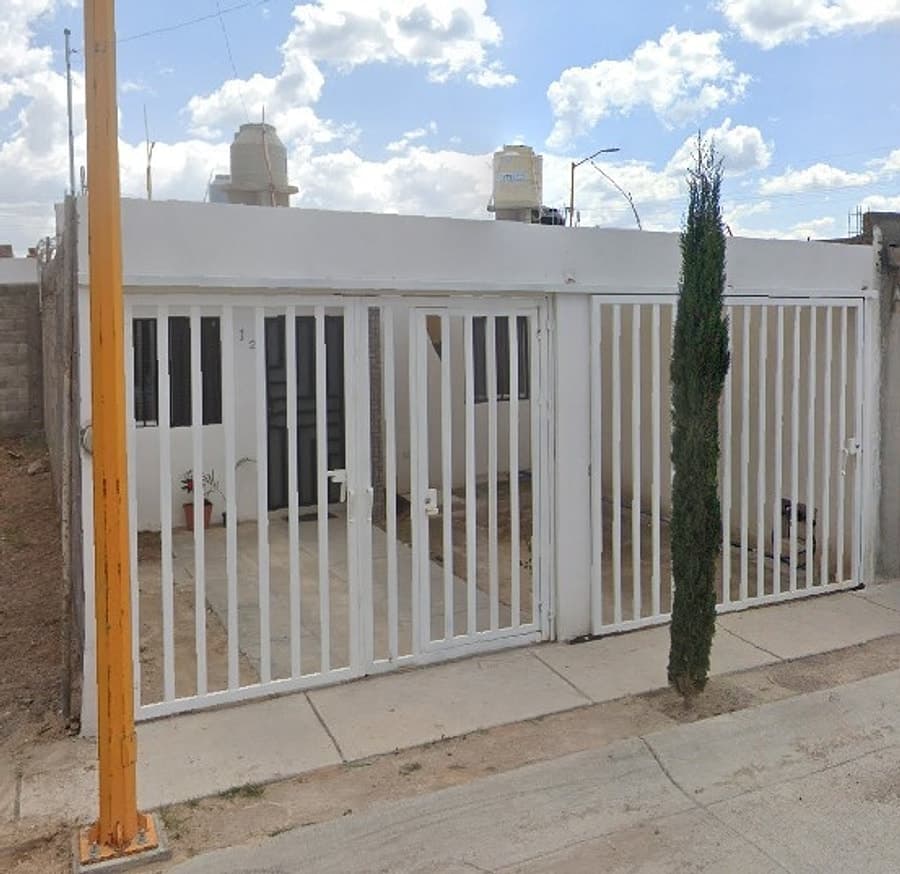Fachada blanca con portón y reja