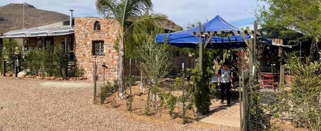 Casa de piedra y jardín con pérgola, al pie del cerro