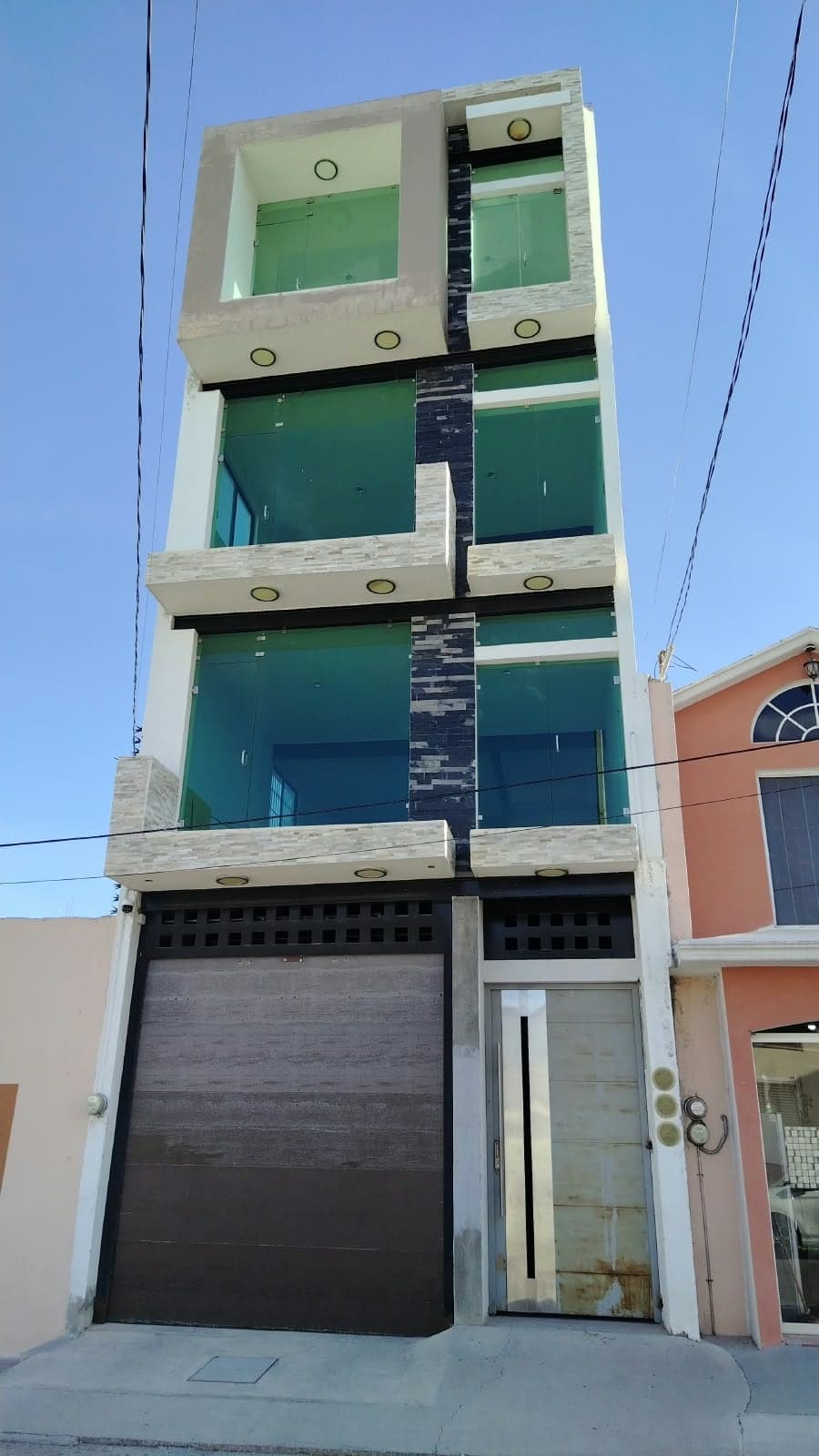 Fachada del edificio con cristales verdes y cortina metálica